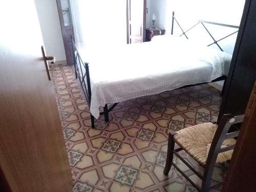 a room with a bed and a chair and a tile floor at Casa Levante in Castelbuono