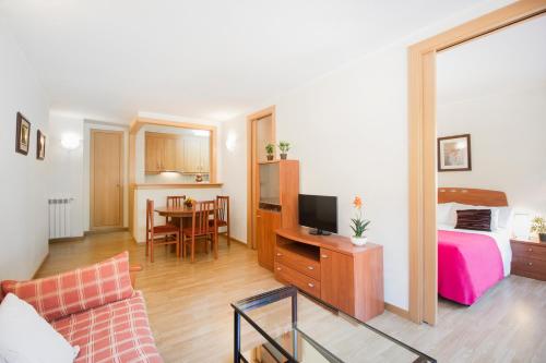 a living room with a bed and a desk with a tv at Apartaments Les Terrasses del Tarter in El Tarter