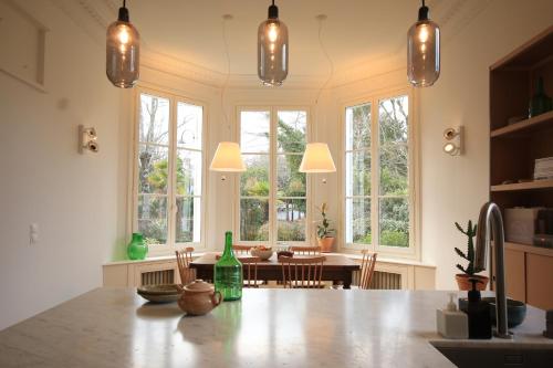 a kitchen with a large table with chairs and windows at Le Quatre Allée Stella Arcachon in Arcachon