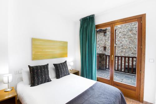 a bedroom with a bed and a large window at Apartaments Les Terrasses del Tarter in El Tarter