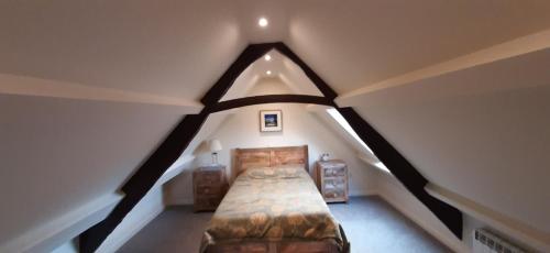 a attic bedroom with a large bed in a room at The Curtain 13th Century Cottage, Gilling West, Richmond in Gilling