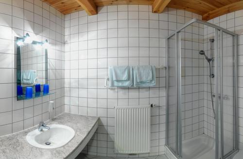 a white tiled bathroom with a sink and a shower at Schlossbrauerei Weinberg - Erste oö. Gasthausbrauerei in Kefermarkt