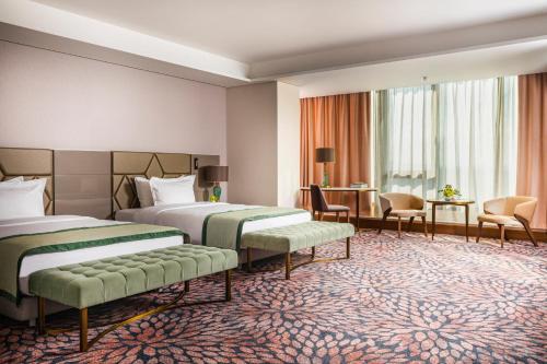 a hotel room with two beds and a living area at Grand Hotel Millennium Sofia in Sofia
