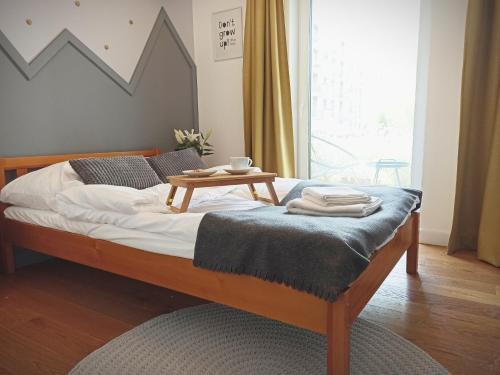 een bed met een houten frame met een tafel erop bij Apartament MIŁOSZA in Ełk