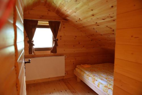 a bedroom in a log cabin with a bed and a window at Tara Place - Camp Rabrenovic in Mojkovac