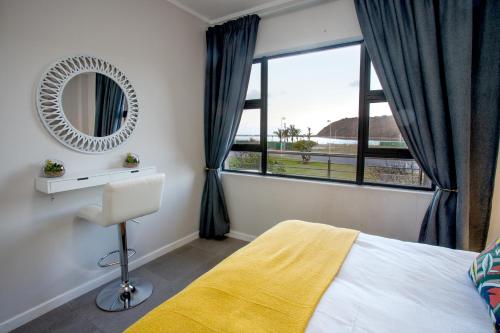a bedroom with a bed and a mirror and a window at Stay at The Point - Beach Beauitful Bliss in Durban