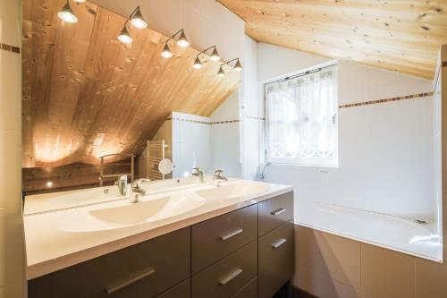 a bathroom with a sink and a tub and a mirror at Residence les chalets de Flaine Hameau - maeva Home in Flaine