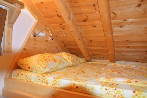 a bed with a pillow in a wooden room at Tara Place - Camp Rabrenovic in Mojkovac