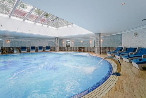 プーシキンにあるTsar Palace Luxury Hotel & SPAの- 青い椅子付きの客室内の大きな水プール
