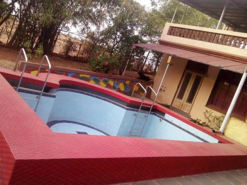 a swimming pool with swings in front of a house at MTDC Meghdhanush park in Igatpuri