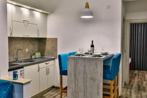 a kitchen with blue chairs and a table with wine glasses at De Lux Apartments Luka in Bar