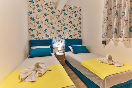two beds in a room with blue and yellow at De Lux Apartments Luka in Bar