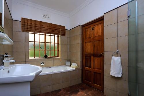 a bathroom with a tub and a sink and a window at Orange-Ville Lodge & Guesthouse in Stellenbosch