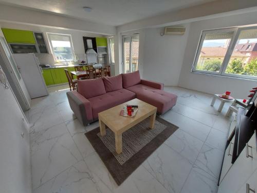 a living room with a purple couch and a table at XXL APARTMENTS CiTY CENTAR 1 in Bitola