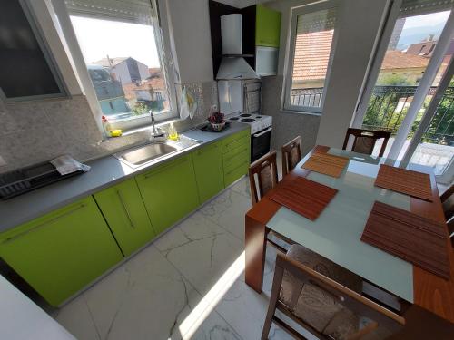 a kitchen with green cabinets and a table with chairs at XXL APARTMENTS CiTY CENTAR 1 in Bitola