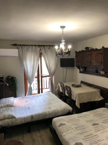 リモーネ・ピエモンテにある1400 Emozioniのベッドルーム1室(ベッド2台、テーブル、窓付)