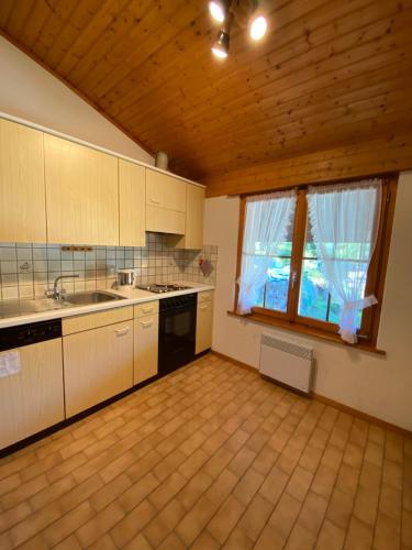 a kitchen with white cabinets and a wooden ceiling at Sorgenfrei in Schwarzsee