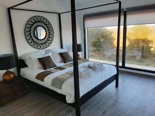 ein Schlafzimmer mit einem großen Himmelbett und einem Spiegel in der Unterkunft Cairnvillas - Villa Solar C37 Luxury Villa with Swimming Pool near Beach in Aljezur