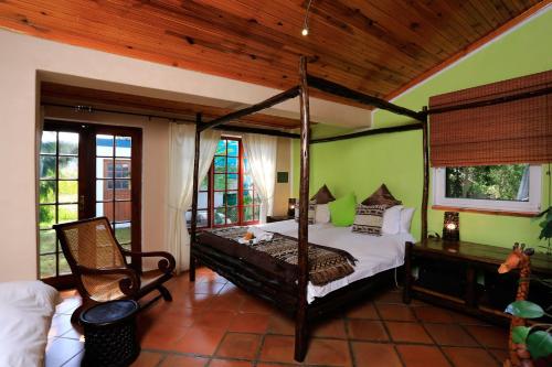 ein Schlafzimmer mit einem Himmelbett und einem Stuhl in der Unterkunft Orange-Ville Lodge & Guesthouse in Stellenbosch