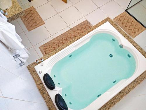 uma banheira de hidromassagem numa casa de banho em azulejo com uma cor turquesa em Arraial da Lage Hospedaria em Resende Costa