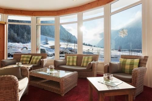 a living room with chairs and tables and a large window at Hotel Gasteigerhof in Neustift im Stubaital