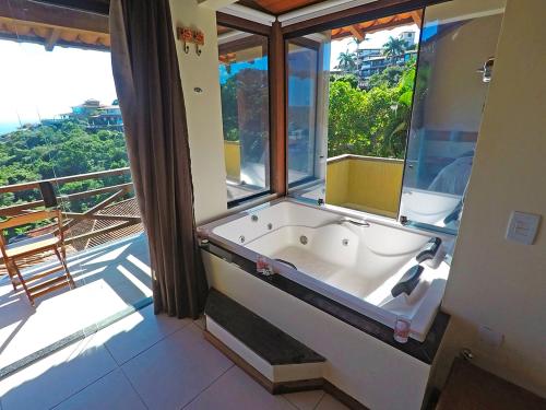 uma banheira num quarto com uma grande janela em Pousada Amancay em Búzios