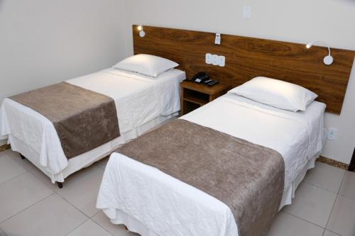 um quarto de hotel com duas camas e uma mesa em San Diego Lancaster Teófilo Otoni em Teófilo Otoni