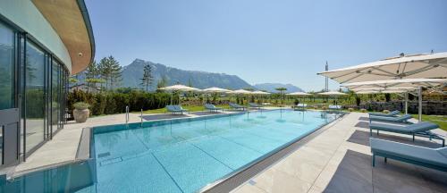 ein großer Pool mit Stühlen und Sonnenschirmen in der Unterkunft Laschenskyhof Hotel & Spa in Wals