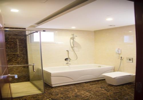 a bathroom with a tub and a shower and a toilet at Carawan Hotel Jeddah in Jeddah