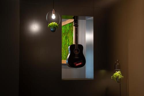 a guitar hanging on a wall next to a mirror at Ibis Hotel Plzeň in Plzeň