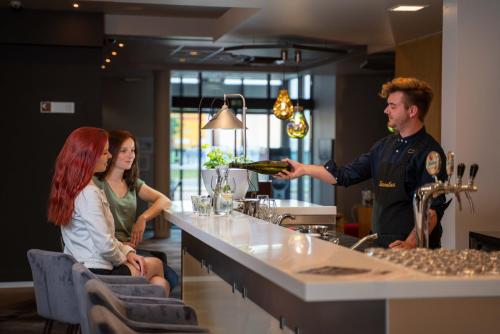 a man holding a bottle of wine at a bar at Ibis Hotel Plzeň in Plzeň