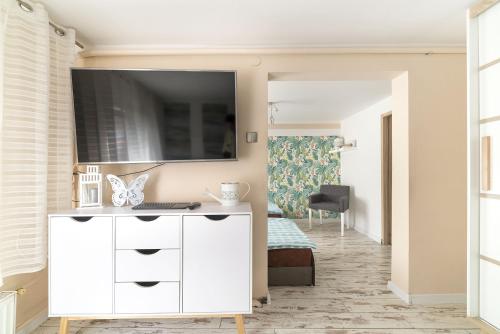 ein Wohnzimmer mit einer weißen Kommode und einem TV an der Wand in der Unterkunft Wera Domki in Jastarnia
