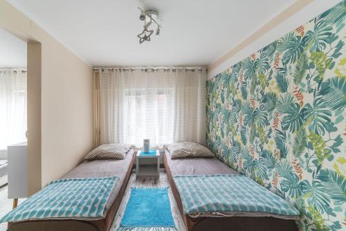 Zimmer mit 2 Betten und einer Wand mit tropischen Tapeten in der Unterkunft Wera Domki in Jastarnia