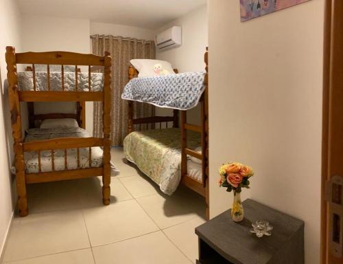 a room with two bunk beds and a vase with flowers at Arraial do cabo in Arraial do Cabo