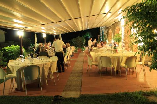 un restaurante con mesas y sillas blancas y gente por la noche en Villa Govi, en Diano Castello