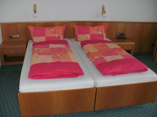 2 camas en una habitación con almohadas rojas y naranjas en Pension zur Traube 3 Sterne, en Oberschwarzach