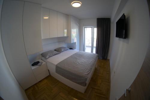 a small bedroom with a bed and a window at Apartman Sunlight in Trebinje