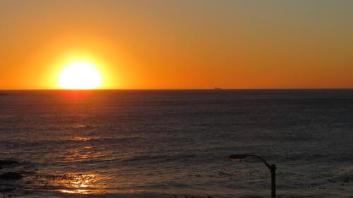 an orange sunset over the ocean with a street light at Azamare Guest House in Cape Town