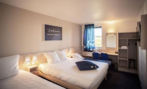サロン・ド・プロヴァンスにあるAce Hôtel Salon de Provenceのベッド2台と窓が備わるホテルルームです。