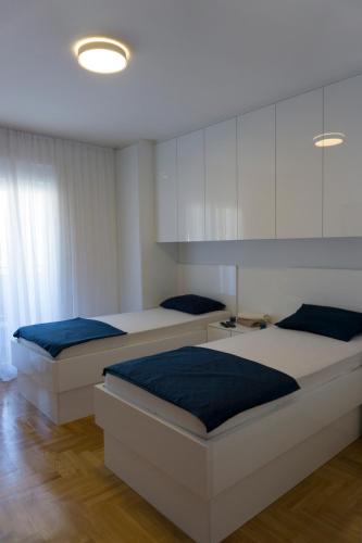 a bedroom with two beds and a white cabinet at Apartman Sunlight in Trebinje