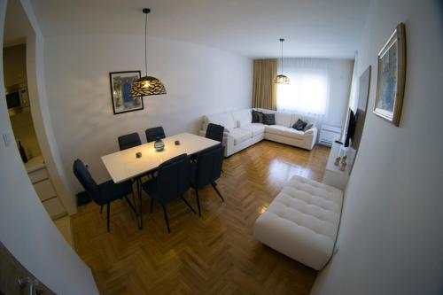 Apartman Sunlight في تريبينيي: غرفة معيشة مع طاولة وكراسي وأريكة