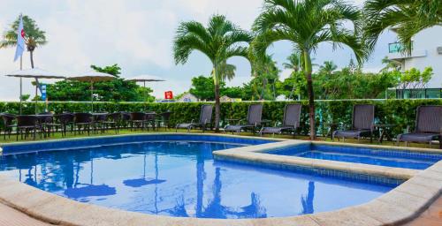una piscina con sillas y palmeras en Nord Luxxor Cabo Branco en João Pessoa
