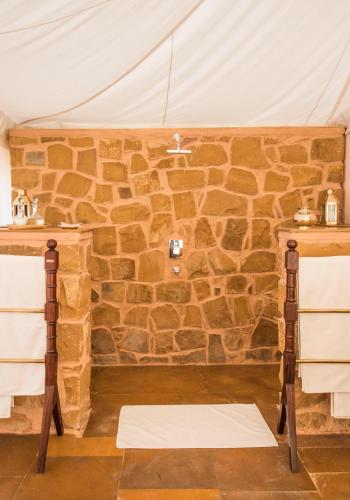 a room with a stone wall in a tent at SUJÁN The Serai Jaisalmer in Jaisalmer