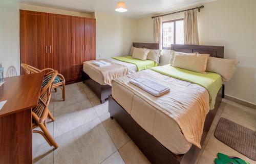 um quarto de hotel com duas camas e uma secretária em Joy Palace Hotel em Nairobi