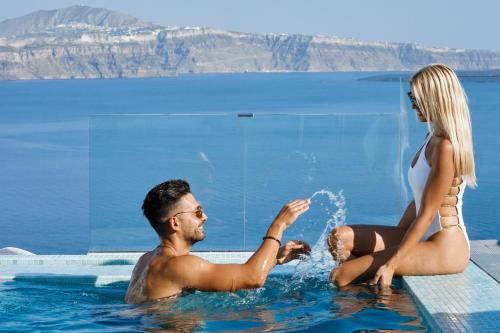a man and a woman sitting in a swimming pool at Filotera Suites in Oia