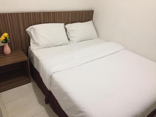 a bed with white sheets and pillows in a room at Fragrance Hotel Johor Bahru in Skudai