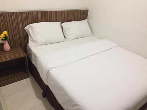 Bett mit weißer Bettwäsche und Kissen in einem Zimmer in der Unterkunft Fragrance Hotel Johor Bahru in Skudai