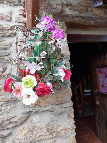 a bunch of flowers in a bird cage on a stone wall at Casa do Trapo in Abrantes