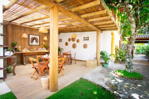 un patio con pérgola de madera, mesa y sillas en Pousada Por do Sol, en Trancoso