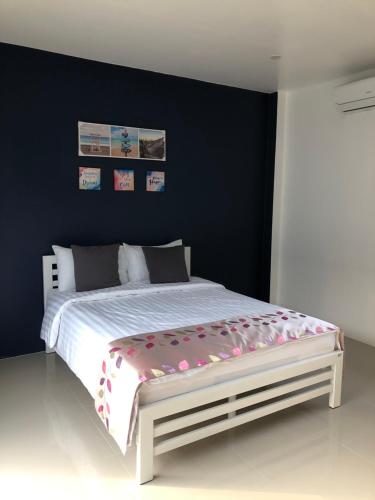 a bedroom with a white bed with a blue wall at SiRi Resort in Maha Sarakham